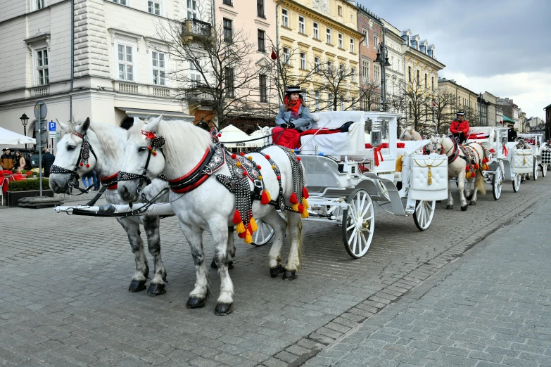 two white horses pulling a carriage with red and gold decorations