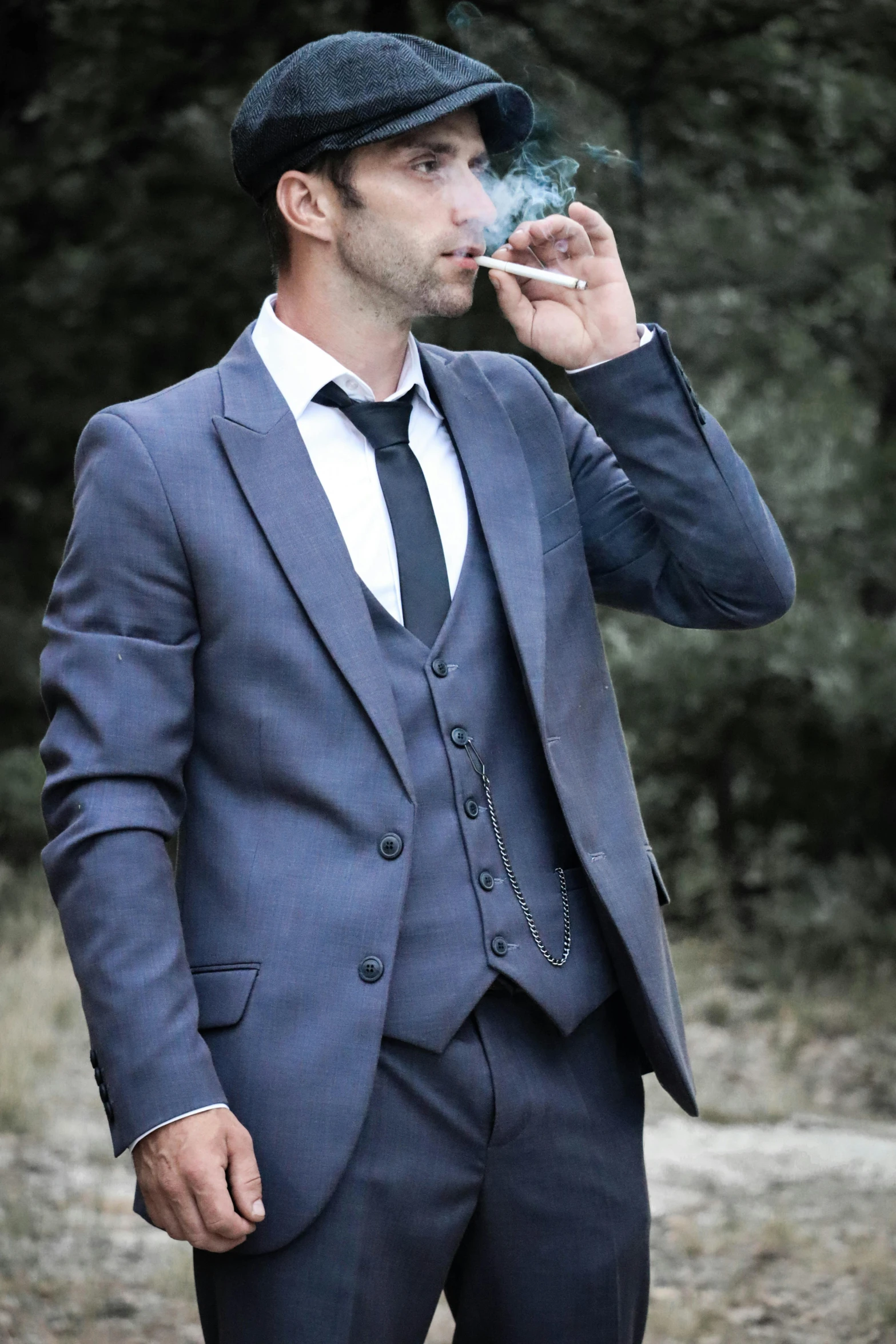 a man in a suit smoking while wearing a hat
