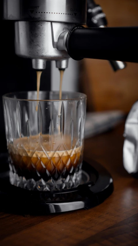 espresso pouring coffee into clear glass cup