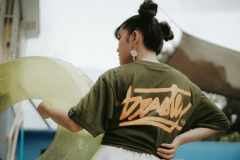 a woman is holding a large umbrella and wearing a shirt with graffiti writing on it