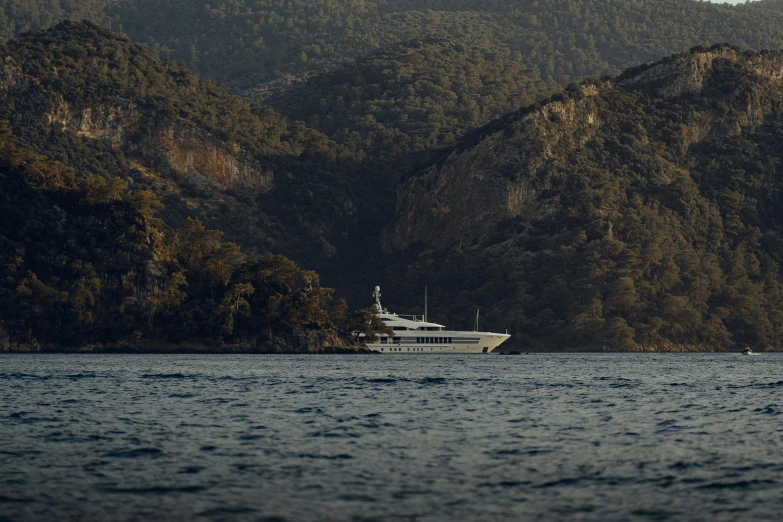 a large white ship floating next to a mountain