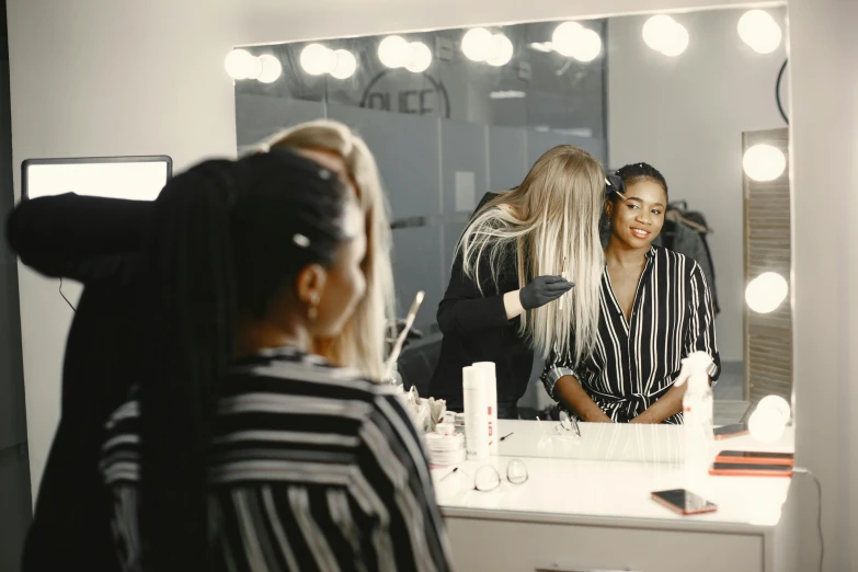 two women doing makeup in front of a mirror