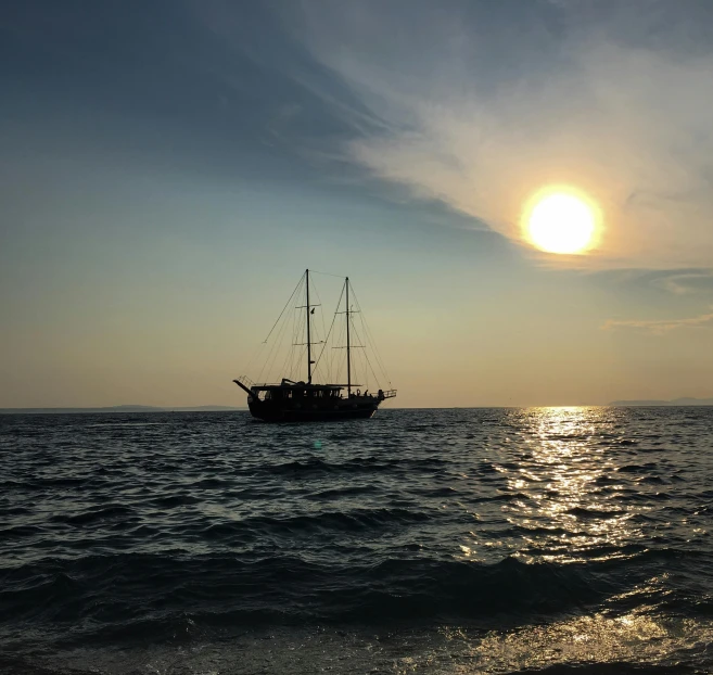 a sailboat is out in the water at sunset