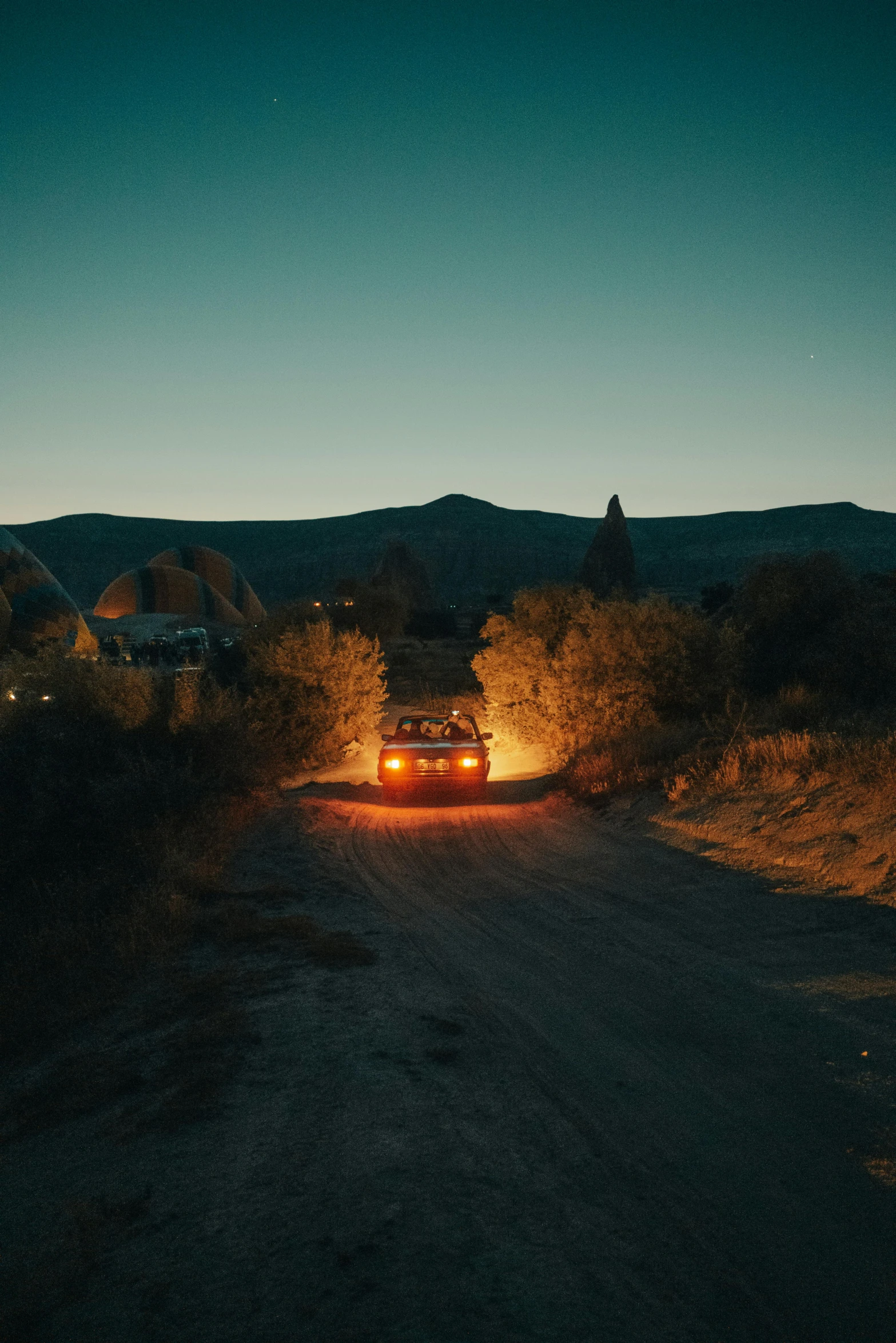 a car driving down a dirt road with trees