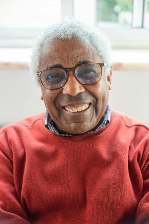 an older person in glasses smiling with one eye closed