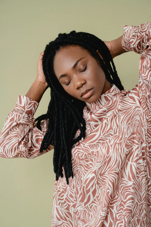 a young black woman is holding her hair up in a relaxed pose