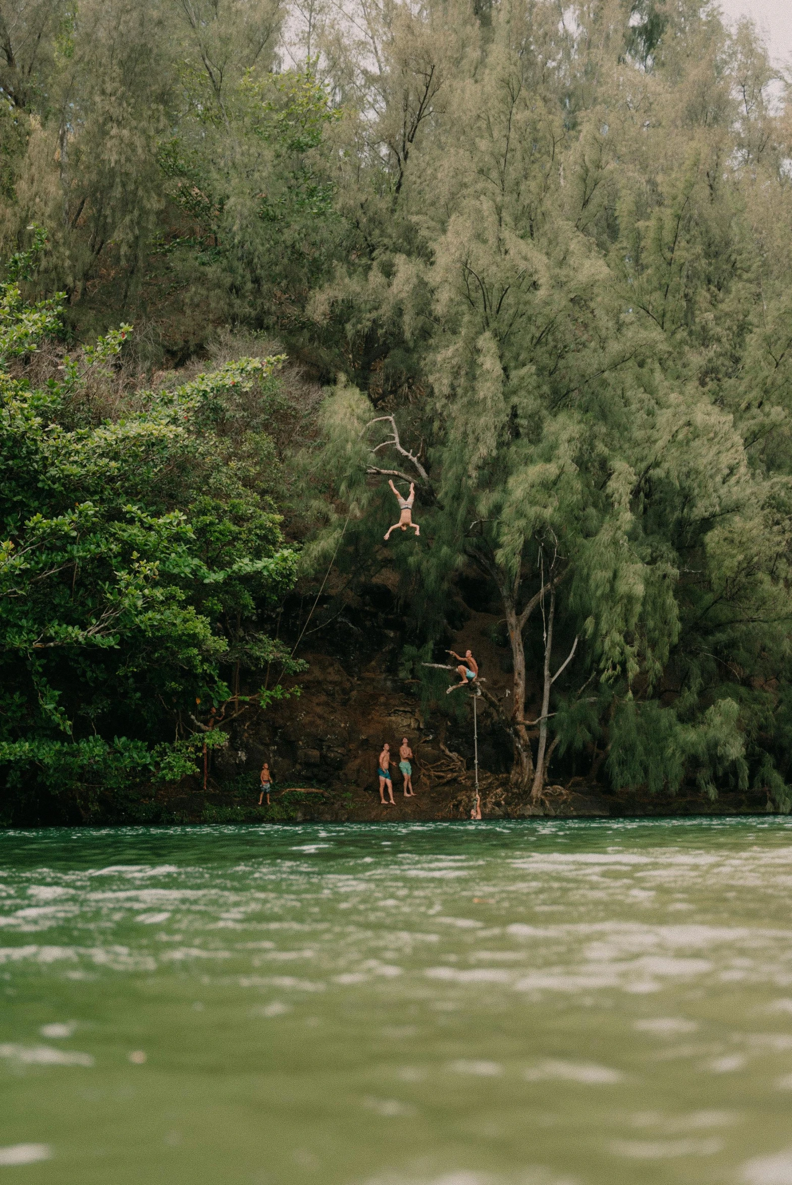 two men are jumping from a boat in the river