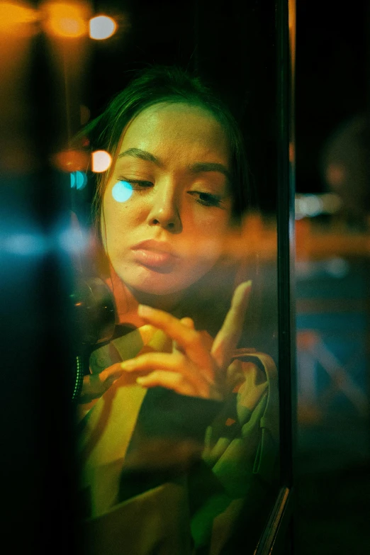 the girl looks down at her phone as she waits for a bus