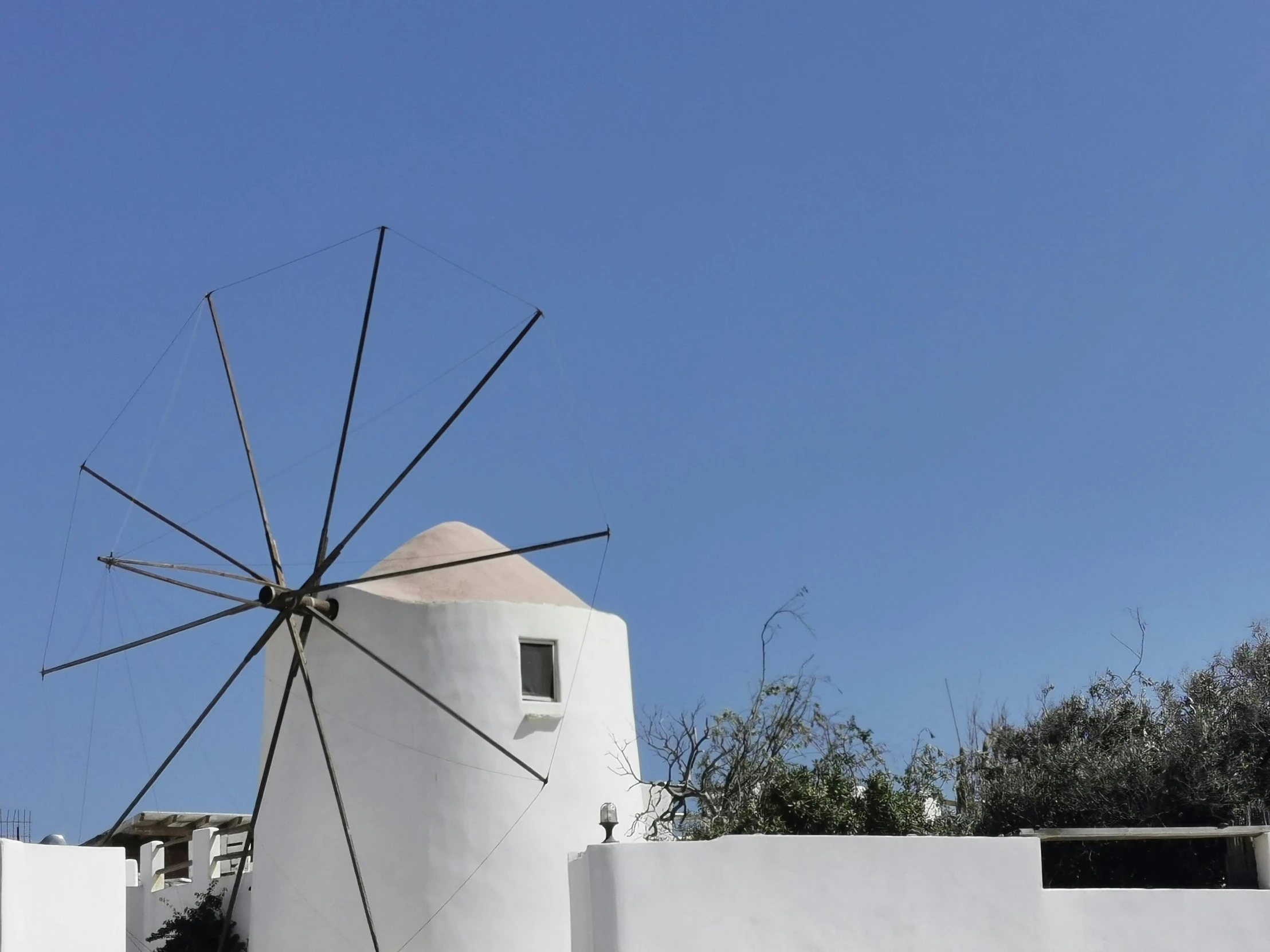 an outdoor windmill is leaning against a white wall