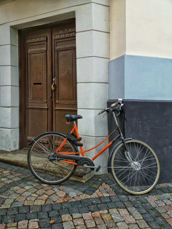 an orange bike leaning against the side of a building