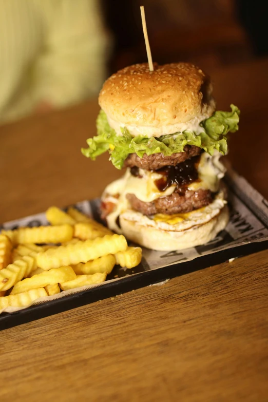 a very big hamburger and fries on a tray