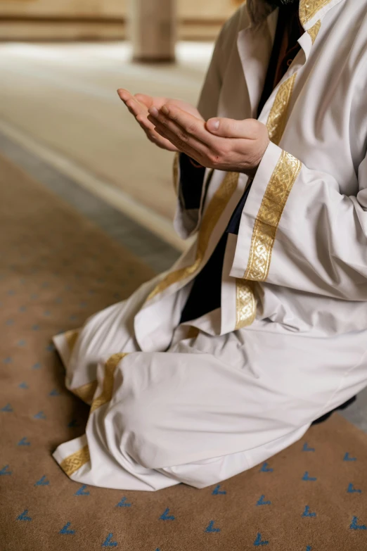 a person wearing white and gold kneeling on the ground