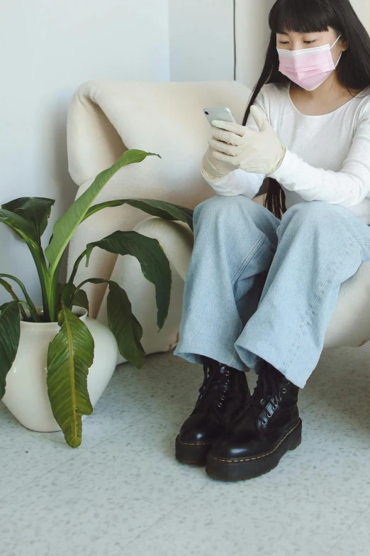 a young woman sitting on a white couch using a cell phone