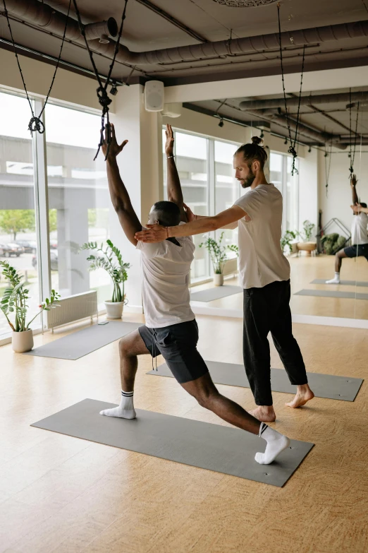 a man hanging on a rope while another person stands in front of him