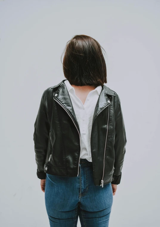 a woman is in her 20s, wearing a green leather jacket