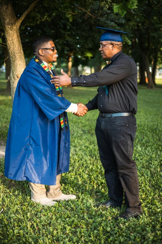 two men who are wearing blue and standing in the grass