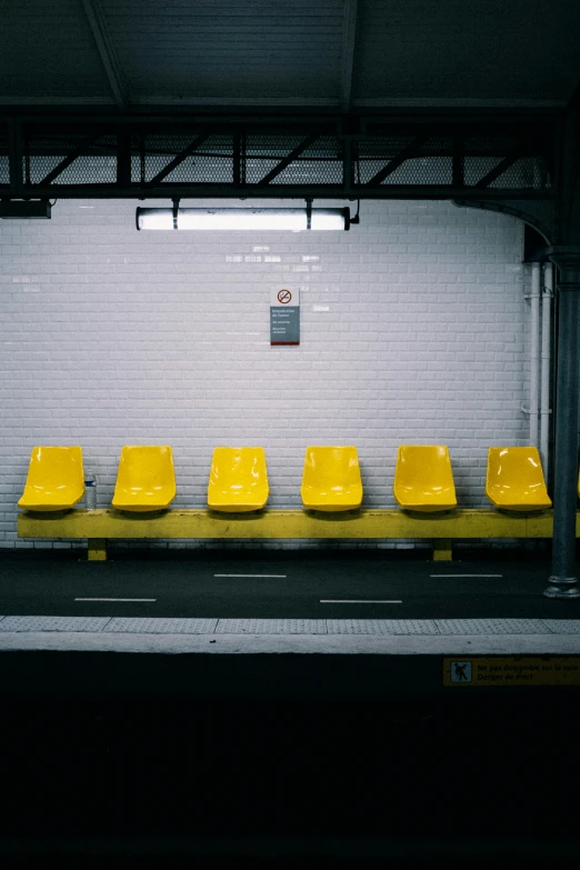 a row of yellow seats next to a white brick wall