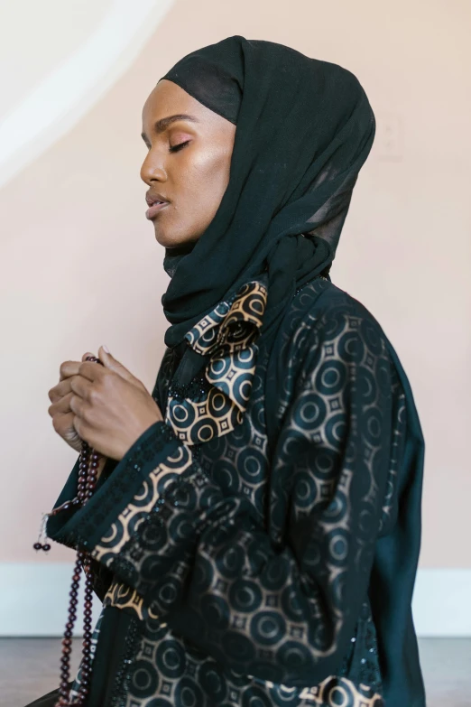 a young woman dressed in a black dress and a blue head scarf