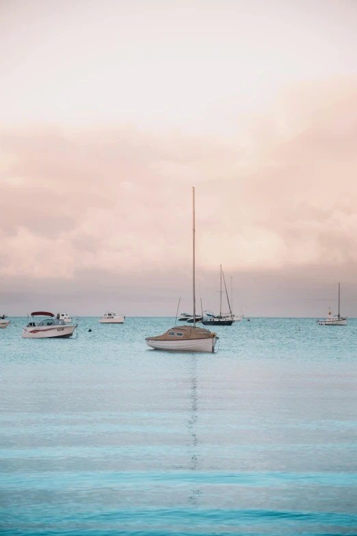 small boats float through a blue sea during the day