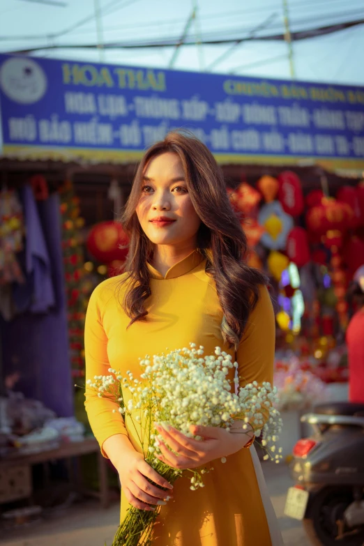 woman in yellow dress holding bunch of white flowers