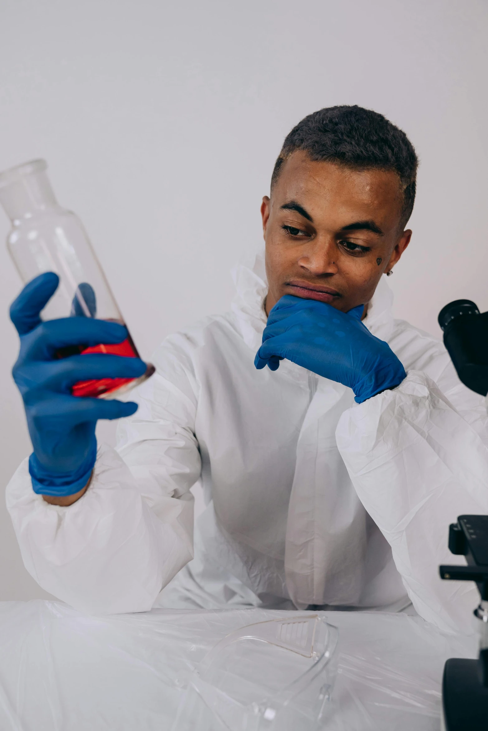 a person in white lab coat and blue gloves holding soing