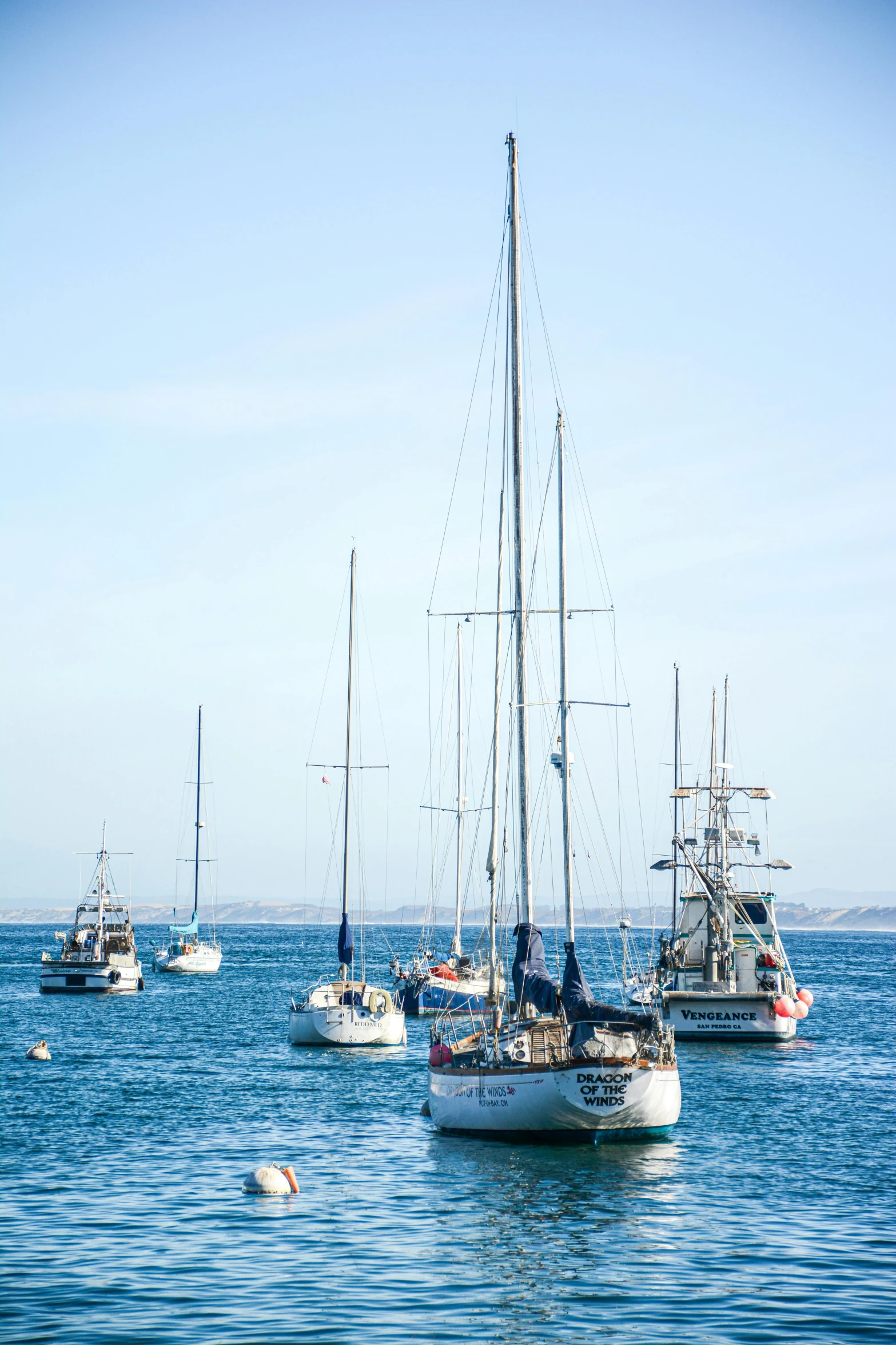 sail boats in the ocean surrounded by rocks and sand