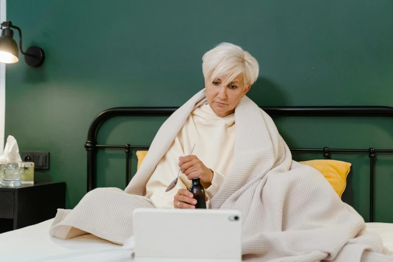 an older lady is sitting in bed using a laptop