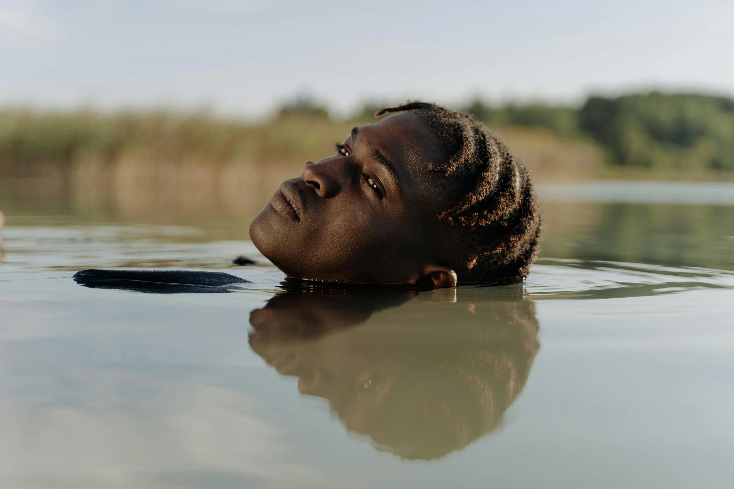 a young man is floating in the water with his head above water