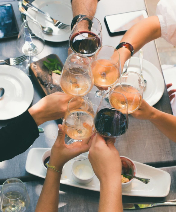 people toasting glasses at a table with white plates and silver utensils