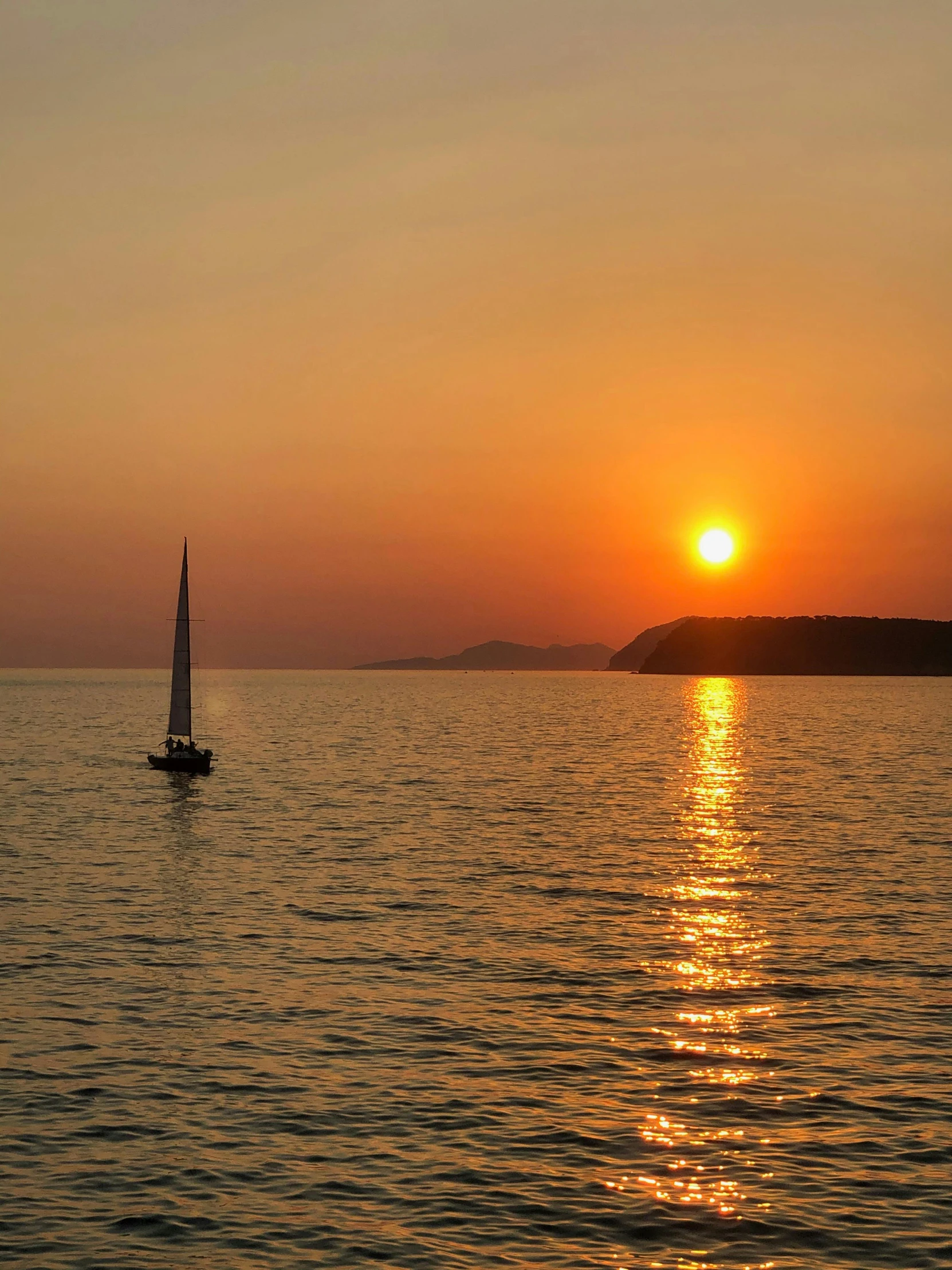 the sun rising behind the horizon over a body of water