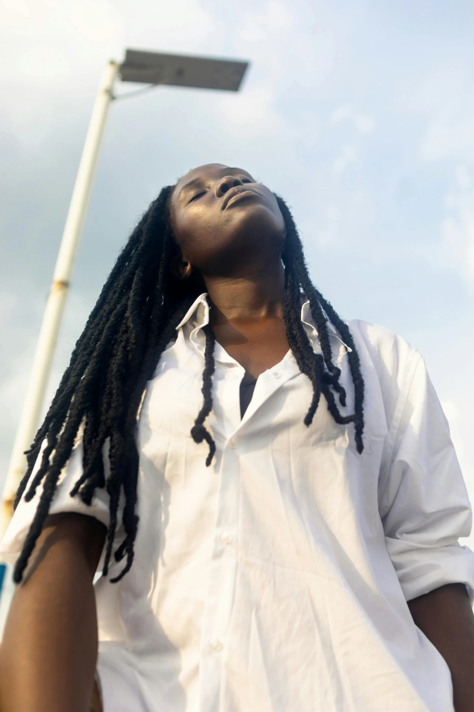 a person with some dreadlocks is standing under a street light