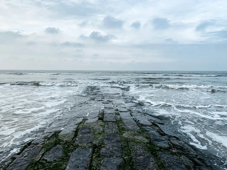 waves crash on the sandy beach near rocks