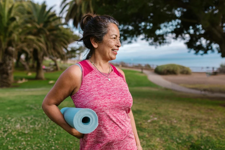 a woman holds an exercise tape next to the ocean