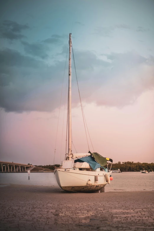 a small sailboat is on the beach by the pier