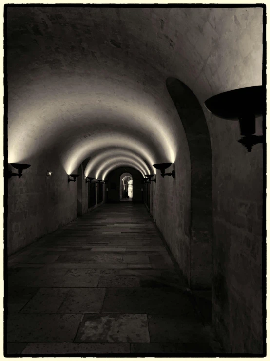 a narrow hallway in black and white with lights on