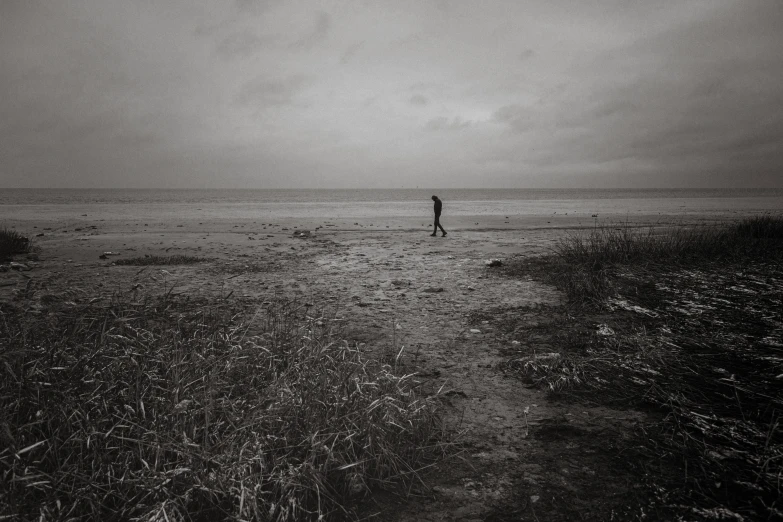 man standing alone on a beach in black and white