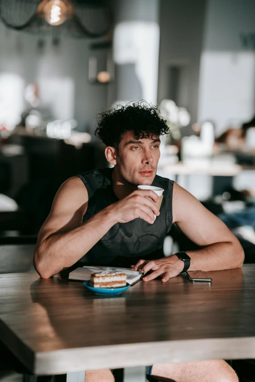 a man in a black tank top sitting at a table with food