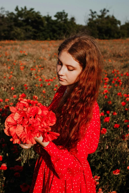 the girl is holding a bouquet of red flowers