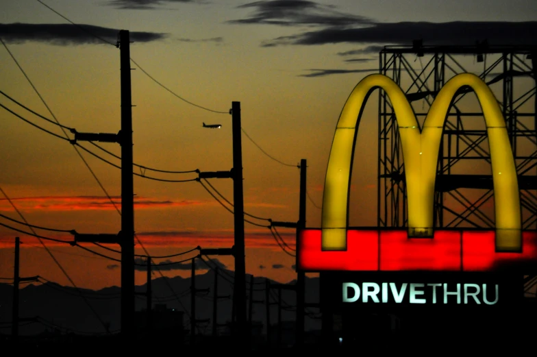 a sunset picture with an electric wire and a large neon sign for a restaurant