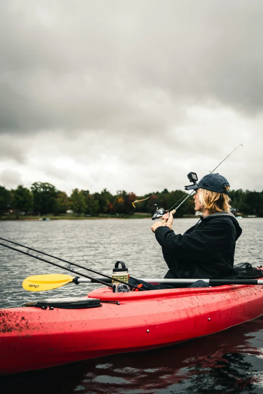 a woman is sitting on her kayak while fishing