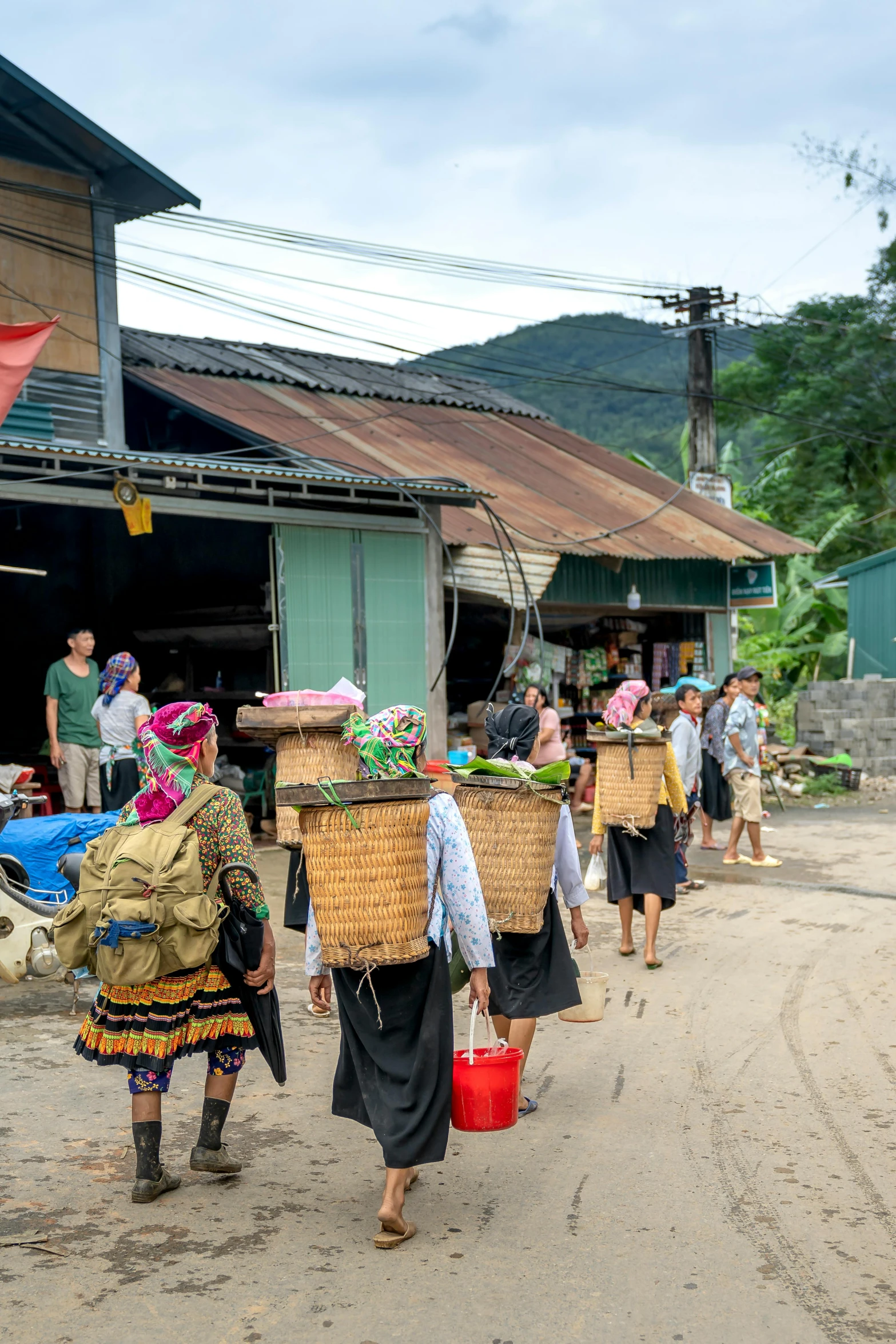 several people carrying baskets on their heads and a woman holding a bucket with soing