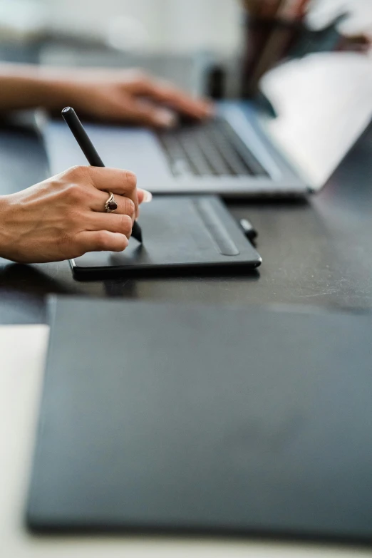 a woman using a laptop with her hand writing