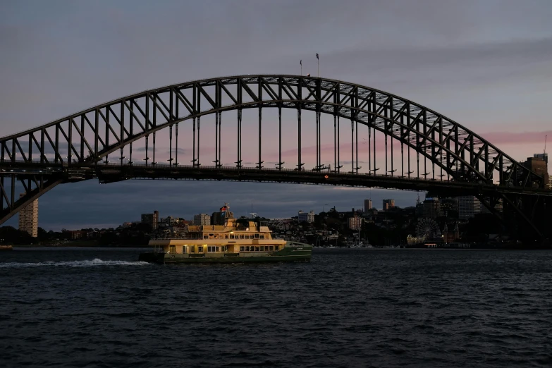 a ferry travels under a large bridge over water