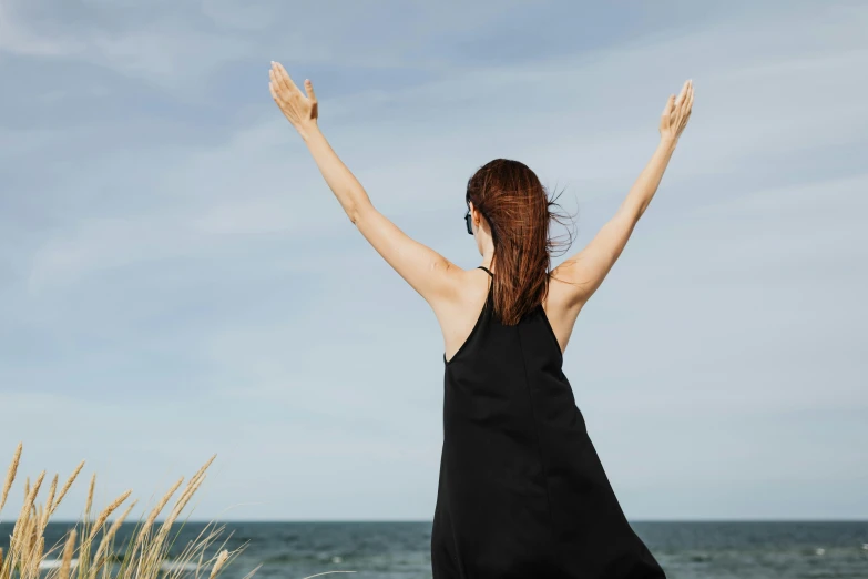 a woman raises her arms to catch the waves in the ocean