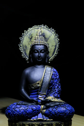 a buddha statue with a gold and blue hat on