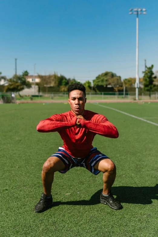 a man kneeling down on a grass covered field