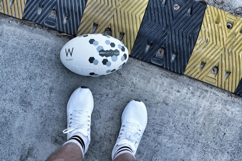 someone's feet and a basketball sitting next to a street curb