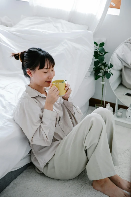 a woman drinking a cup of coffee sitting on the floor