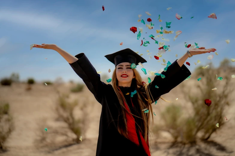 a woman wearing graduation clothing throwing confetti in the air