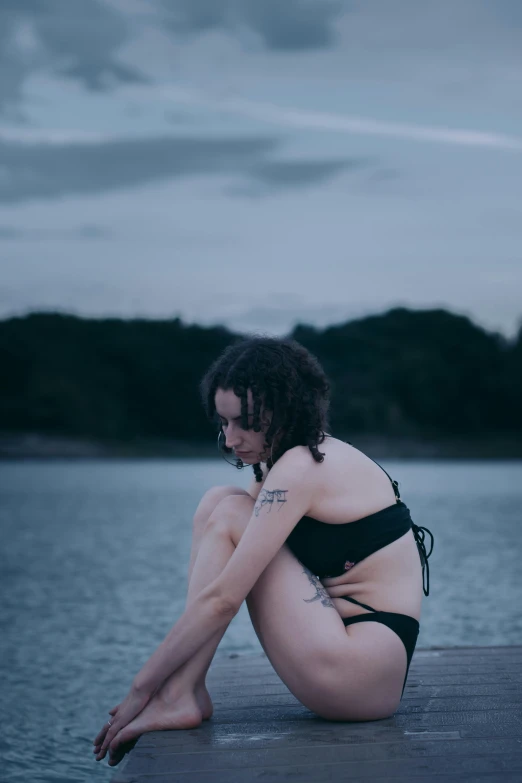 a woman that is sitting down on the edge of a dock